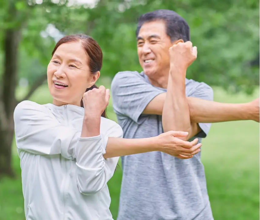 A man and a woman stretching arms/shoulder outdoors