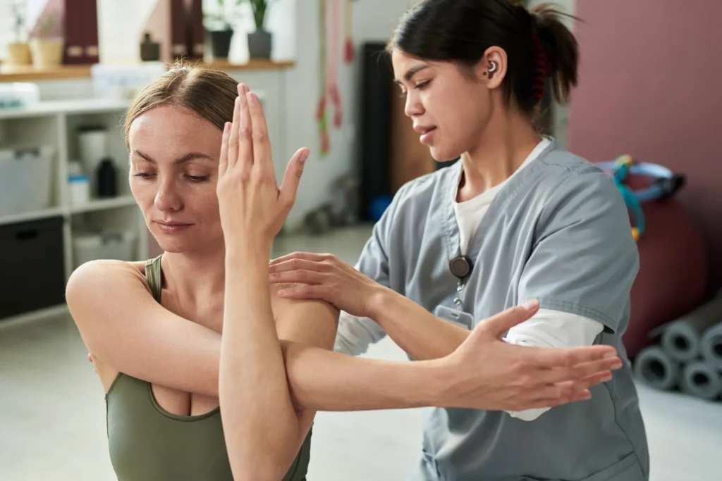 Assistant helping woman with shoulder movement